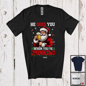 MacnyStore - Personalized He Sees You Drinking; Humorous Christmas Custom Name Santa Beer Drinking; Drunker T-Shirt