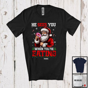 MacnyStore - Personalized He Sees You Eating; Humorous Christmas Custom Name Santa Donut; Food Lover T-Shirt